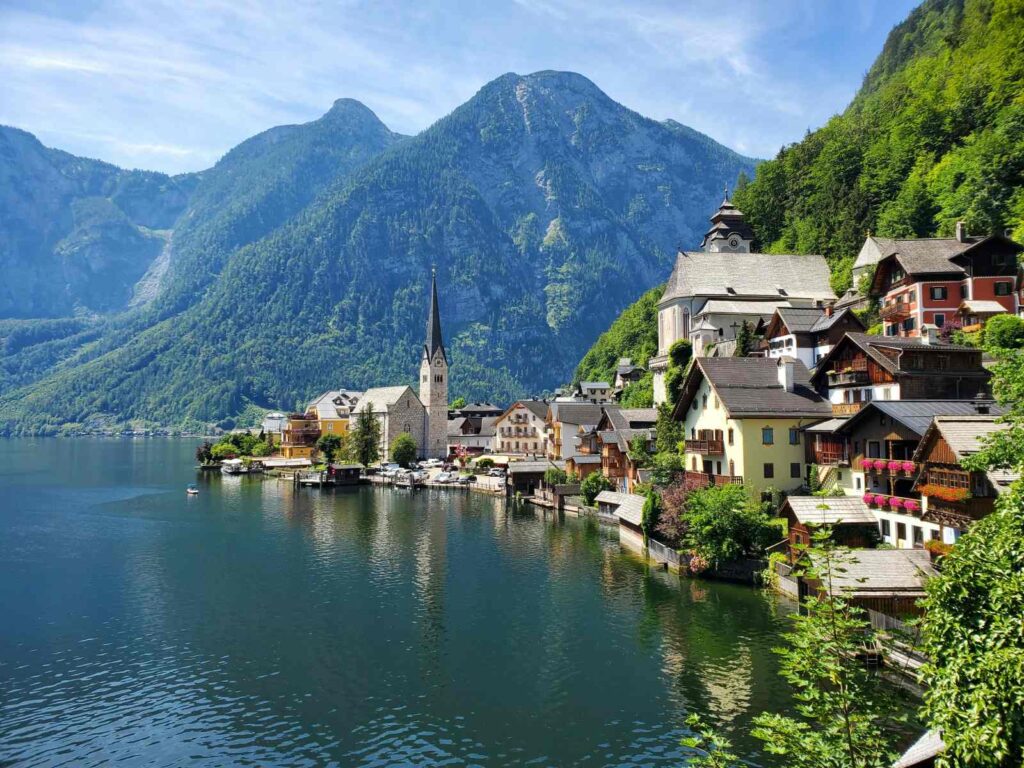 Veduta panoramica di Hallstatt in Austria con lago, montagne e case affacciate sull'acqua, meta ideale per il turismo sostenibile